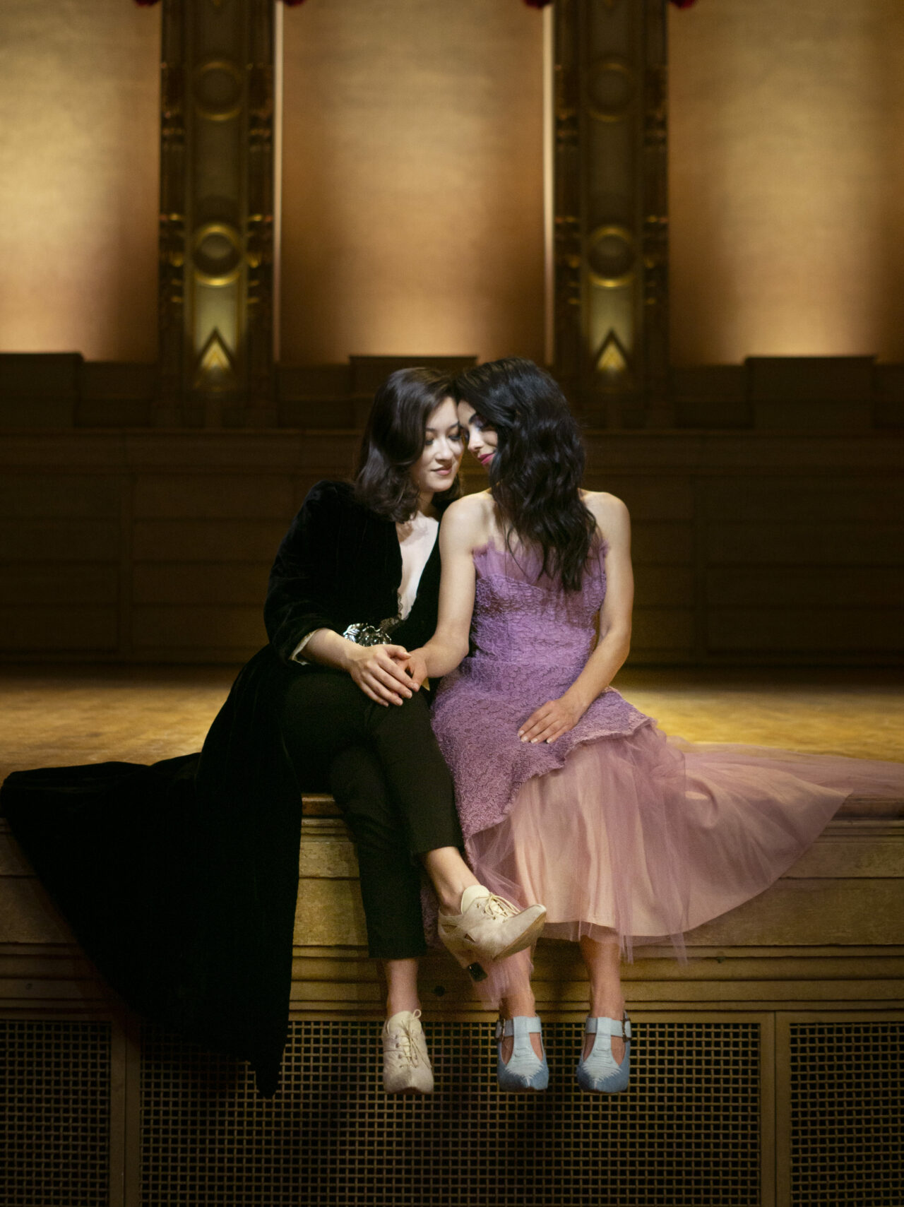 LGBTQ couple sitting on the stage of the Orpheum theatre in Vancouver. Un couple de femmes, assises sur la scène du théâtre l"Orpheum a Vancouver.