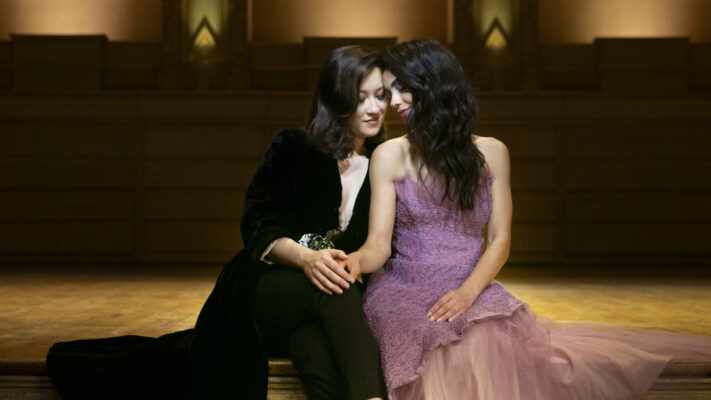 LGBTQ couple sitting on the stage of the Orpheum theatre in Vancouver. Un couple de femmes, assises sur la scène du théâtre l"Orpheum a Vancouver.